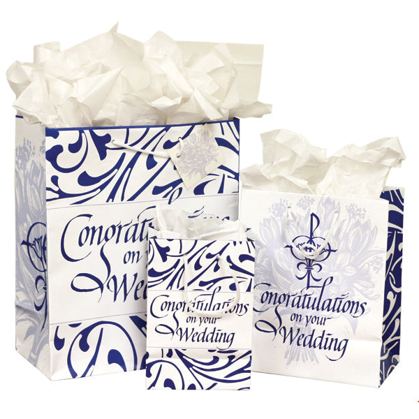 Celebrate the sacrament of matrimony with these beautiful bags. The large and small bags feature a blue filigree design around the message "Congratulations on your Wedding." The sides feature a religious wedding symbol (two flowers and rings joined in a Chi Rho) in dark blue. In the background is a light blue woodcut image of a bouquet of wedding flowers. On the medium bag, the wedding symbol is on the front and back, while the sides are covered with the reverse of the filigree design