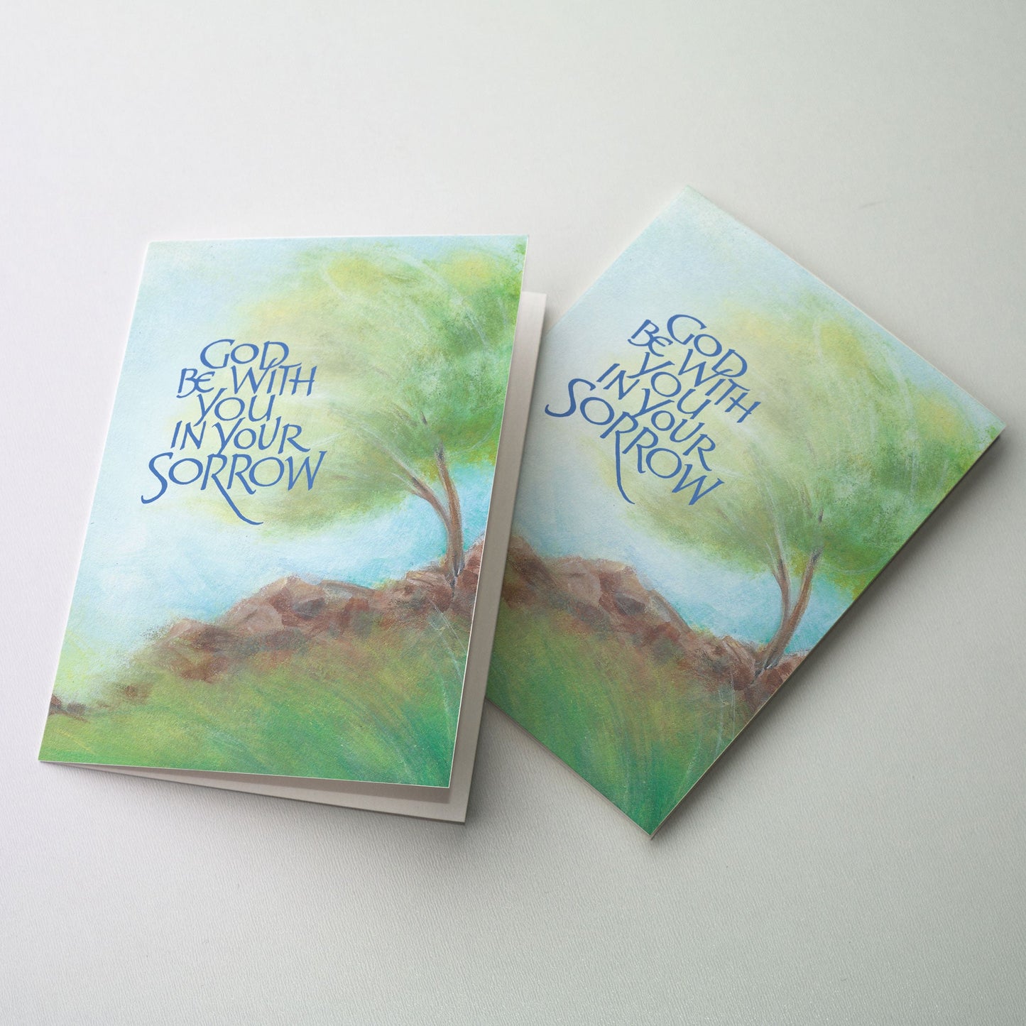 Windswept tree growing on rocks with blue calligraphy