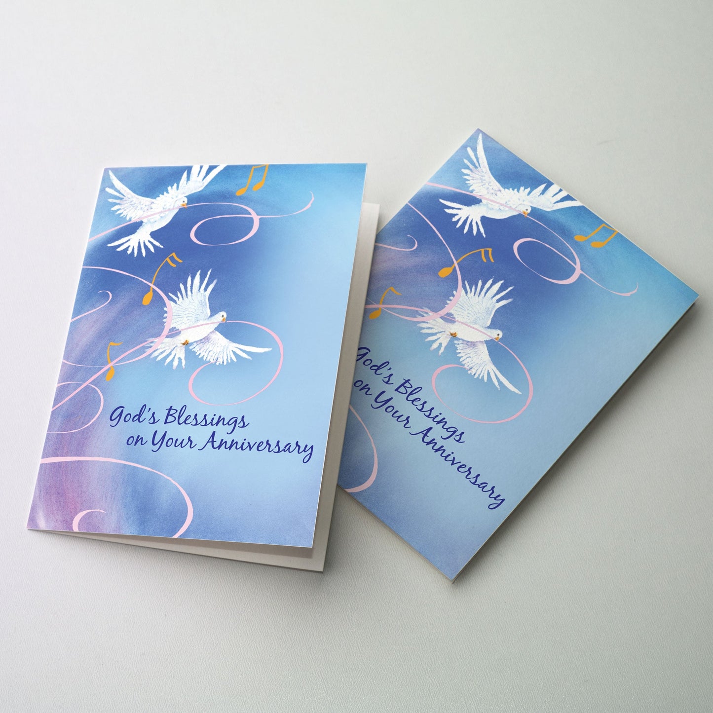 A pair of white doves in flight with ribbons on a blue background.