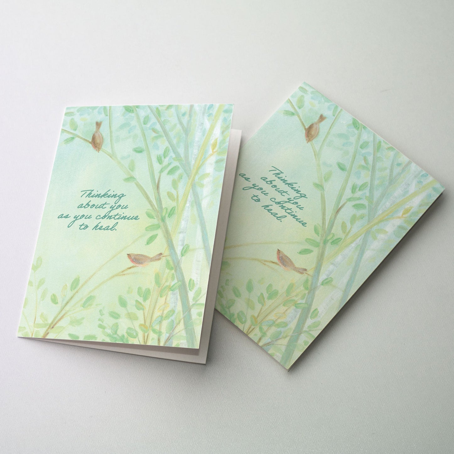 Two robins amid softly painted trees.