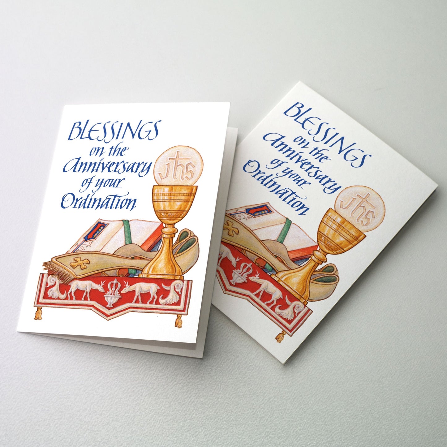 Chalice and host, stole and gospel book on altar; red antependium on altar with image of deer drinking from fountain of life