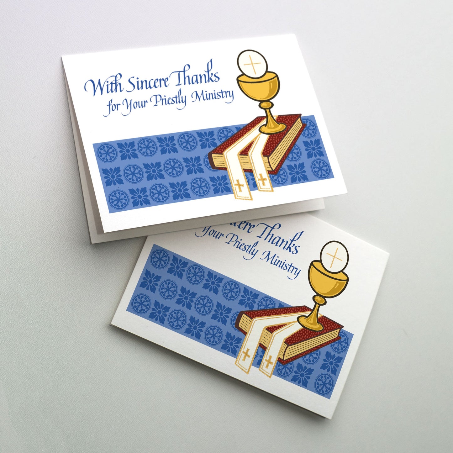 7" x 5". Cup with host, stole and Gospel book on a blue patterned background.