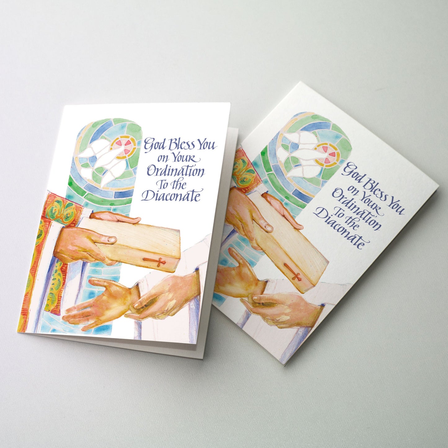 Watercolor image of a bishop placing the book of the Gospels in the hands of a newly ordained deacon. A stained glass window of the Holy Spirit is visible in the background in green and blue shades of glass.