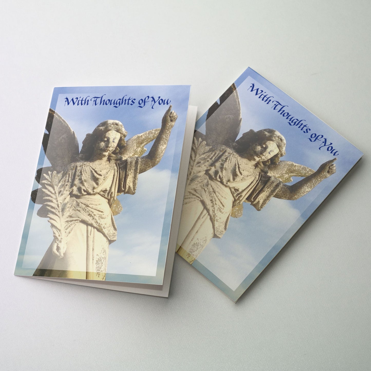 Photo of a statue of an angel with one hand upraised and a palm branch in the other. A blue sky is in the background.